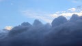 Textured gray clouds on the blue sky. In the background are white clouds illuminated by the setting sun. Royalty Free Stock Photo