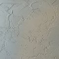Textured gray plaster wall featuring irregular, raised patterns and indentations. The Royalty Free Stock Photo