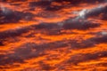 Textured moody clouds, glowing red and orange in the setting sun