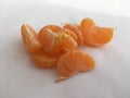 Textured orange mandarin slices scattered on a white background. Still life.