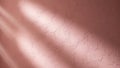 Textured rose gold wall surface with dramatic diagonal light rays casting soft shadows and highlights Keywords Royalty Free Stock Photo
