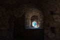 Textured wall of ancient fortress with small round window. Royalty Free Stock Photo