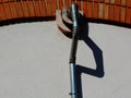 White stucco wall and brick arch with galvanized metal pipe downspout