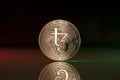 Tezos XTZ crypto coin placed on reflective surface in dark background