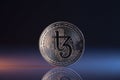 Tezos XTZ Crypto Coin Placed on reflective surface and lit with lights.