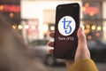 Tezos XTZ cryptocurrency symbol, logo. Business and financial concept. Hand with smartphone, screen with crypto icon