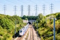 A TGV Duplex high-speed train is entering a tunnel under a row of transmission towers Royalty Free Stock Photo