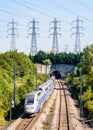 A TGV Duplex high-speed train is entering a tunnel under a row of transmission towers Royalty Free Stock Photo