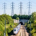 A TGV Duplex high-speed train is entering a tunnel under a row of transmission towers Royalty Free Stock Photo