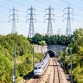 A TGV high-speed train is entering a tunnel under a row of transmission towers Royalty Free Stock Photo