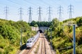 A TGV high-speed train is entering a tunnel under a row of transmission towers Royalty Free Stock Photo