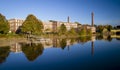 A 19th century textile mill has been renovated for modern use, seen reflected in the neighboring river