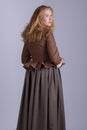 18th century woman in brown outfit on plain studio backdrop Royalty Free Stock Photo