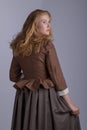 18th century woman in brown outfit on plain studio backdrop Royalty Free Stock Photo