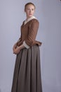 18th century woman in brown outfit on plain studio backdrop Royalty Free Stock Photo