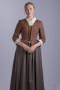 18th century woman in brown outfit on plain studio backdrop Royalty Free Stock Photo