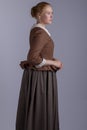 18th century woman in brown outfit on plain studio backdrop Royalty Free Stock Photo