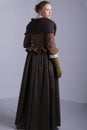 18th century woman in brown outfit on plain studio backdrop Royalty Free Stock Photo