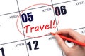 Hand drawing a red circle and writing the text TRAVEL on the calendar date 5 April. Travel planning.