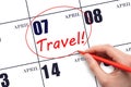 Hand drawing a red circle and writing the text TRAVEL on the calendar date 7 April. Travel planning.