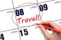 Hand drawing a red circle and writing the text TRAVEL on the calendar date 8 April. Travel planning.