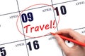 Hand drawing a red circle and writing the text TRAVEL on the calendar date 9 April. Travel planning.