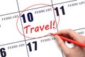 Hand drawing a red circle and writing the text TRAVEL on the calendar date 10 February. Travel planning.