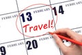 Hand drawing a red circle and writing the text TRAVEL on the calendar date 13 February. Travel planning.