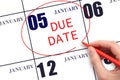 Hand writing text DUE DATE on calendar date January 5 and circling it. Payment due date Royalty Free Stock Photo