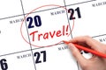 Hand drawing a red circle and writing the text TRAVEL on the calendar date 20 March. Travel planning.