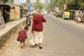 12th December, 2021, Kolkata, West Bengal, India: A little girl trying to help an old man to carry his bag