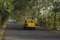17th November, 2021, Narendrapur, West Bengal, India: A beautiful road with road side trees and a famous yellow taxi on move of