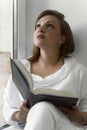 30th woman in white clothes is reading a book by the window. dreamy emotion