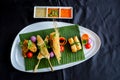 Thai appetizers spring rolls, crispy prawn, Thai sausage, chicken satay on black background.