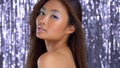 Thai asian model in studio with silver rain disco background and party makeup