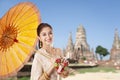 Thai asian women welcome with traditional Thai suit and umbrella on temple background