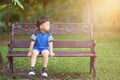 Thai boy sit on bench in park with green botany background Royalty Free Stock Photo