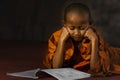 Thai buddhist novice lying on floor reading buddhism book in temple