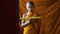 Thai buddhist novice in orange robe standing and reading buddhism lessen scriptur Royalty Free Stock Photo