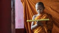 Thai buddhist novice in orange robe standing and reading buddhism lessen scripture Royalty Free Stock Photo