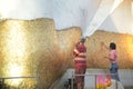 Thai Buddhists Paste gold leaf on the largest Reclining Buddha.