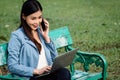 Asian business woman in office uniform Talking on the cell phone with the customer sitting on the table in the park. With a smilin Royalty Free Stock Photo