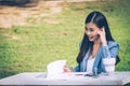 Asian business woman in office uniform Talking on the cell phone with the customer sitting on the table in the park. With a smilin