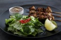 Thai chicken skewers with lime and chili, on black plate Royalty Free Stock Photo