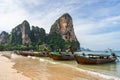 Thai colorful long-tail boats floats in water on the seashore on beautiful picturesque tropical West Railay beach with majestic Royalty Free Stock Photo