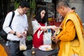 Thai couple making an offering to a Thai monk in the early morning in Bangkok