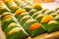 Thai Dessert: Sweet sticky rice with steamed egg custard with topping varieties wrapped with banana leaves package displayed Royalty Free Stock Photo