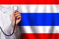Thai doctor's hand with stethoscope on the background of flag of Thailand Medicine, clinic, practitioner, healthcare