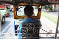 Thai driver driving his Tuk Tuk along Bangkok streets. Royalty Free Stock Photo