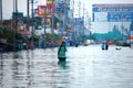 Thai family people natural disaster victims walking wading in water on street of alley while water flood road go receive goods